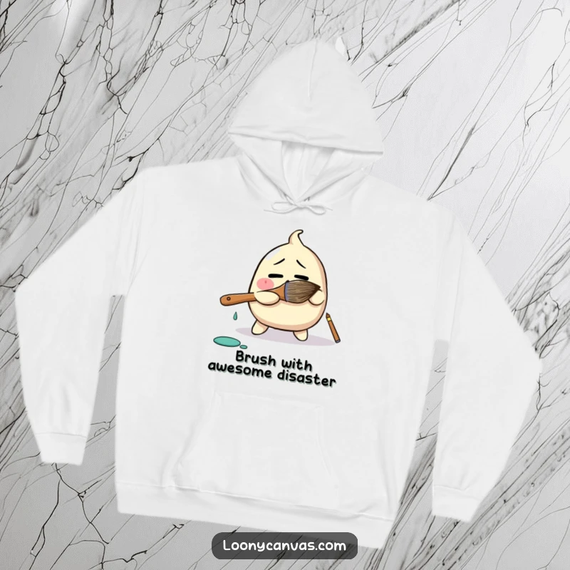 Funny hoodie depicting a bewildered blob character comically wrestling a giant paintbrush, perfect for artists who love humor and warmth.